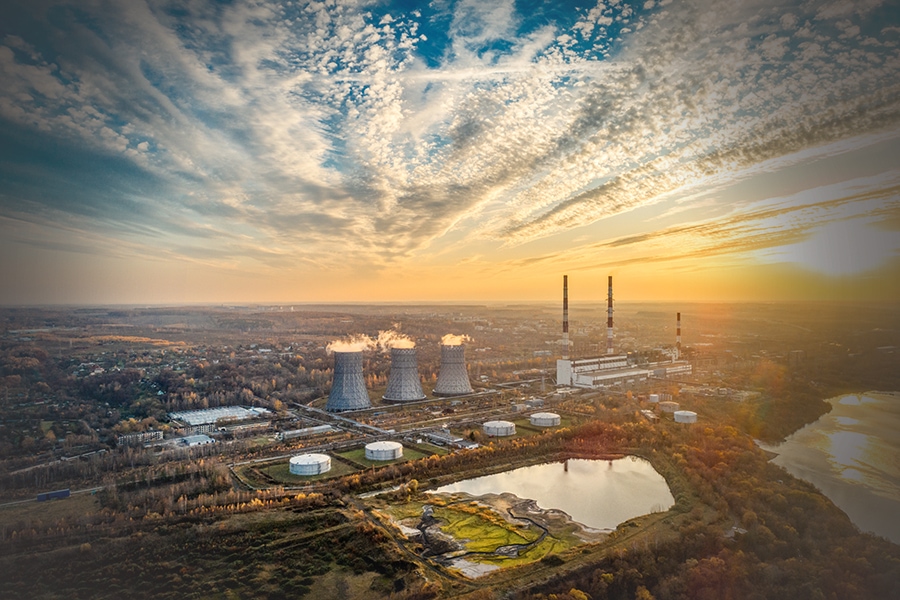 Power plant generating heat and electricity. High pipes and cooling towers are visible. Aerial view. Autumn landscape. Evening shooting at sunset.