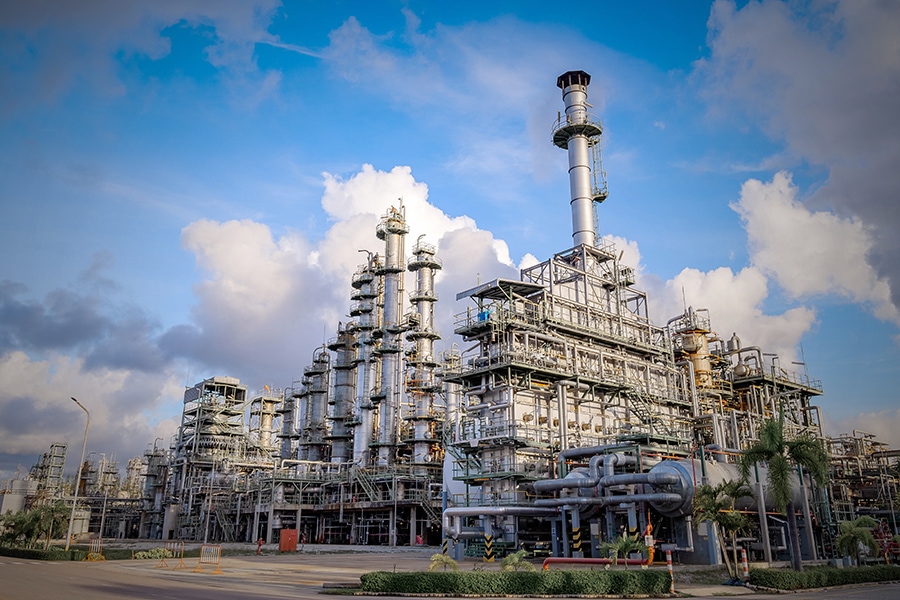 Industrial Furnace And Refinery Column Cracking Hydrocarbons In Factory On blue sky background