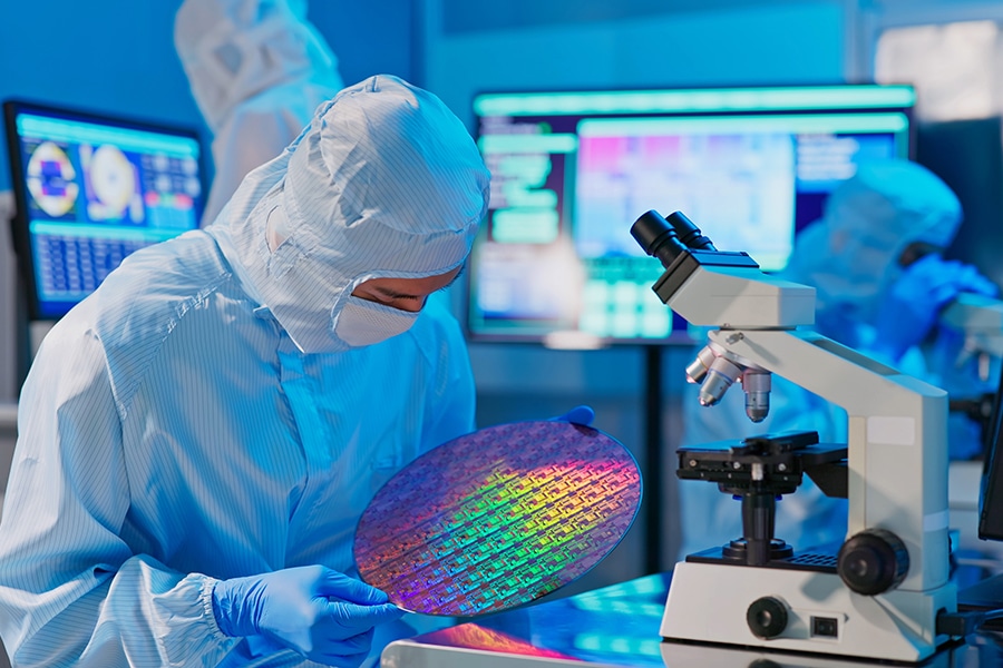 Asian Male Technician In Sterile Coverall Holds Wafer That Reflects
