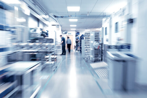 Selection of Gauges, A blurred factory scene featuring several individuals engaged in various activities within the industrial setting.