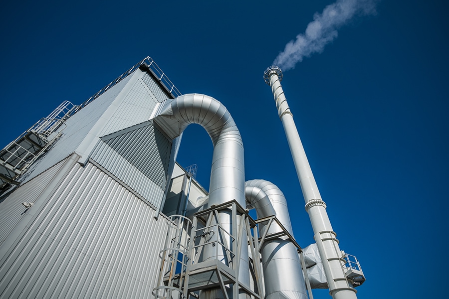 Biofuel boiler chimneys on a blue sky background. Electrostatic precipitator in the foreground