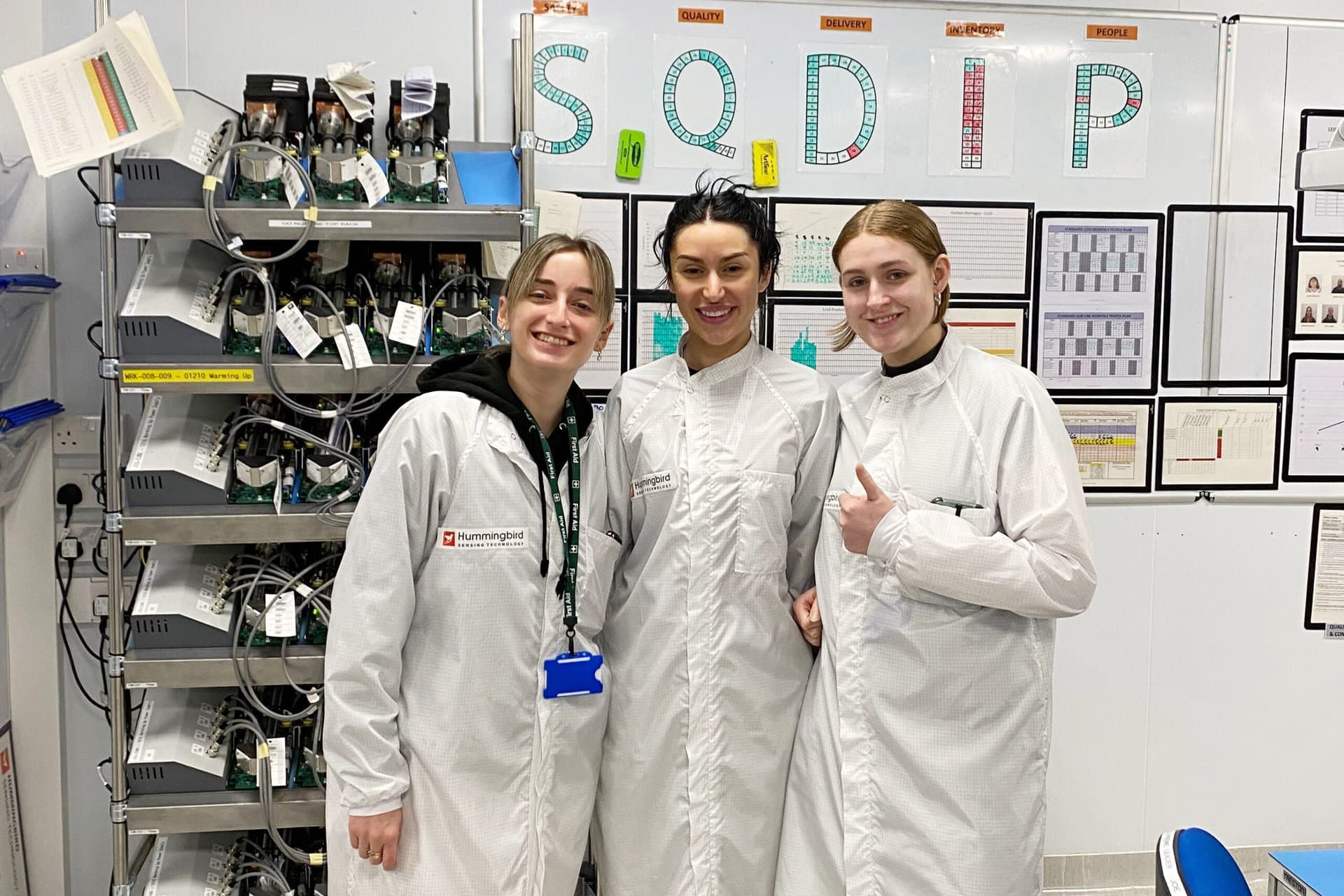 Three women in lab coats stand together, representing a clean room team dedicated to scientific research and innovation.