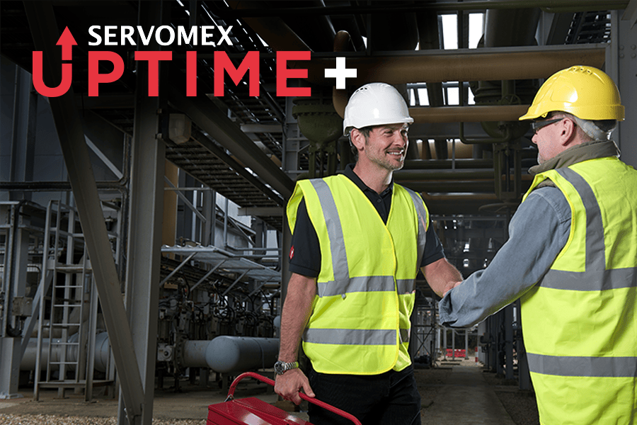 Servomex engineers in safety vests shake hands in an industrial environment, symbolizing collaboration and partnership in safety.