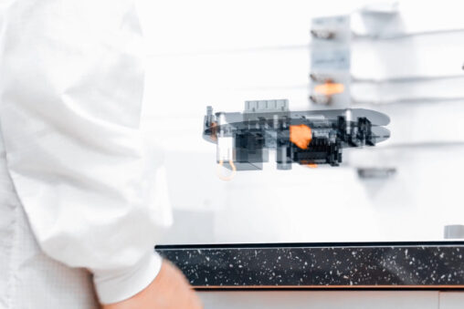 A person in a lab coat stands confidently in front of a complex machine, showcasing a professional laboratory environment.
