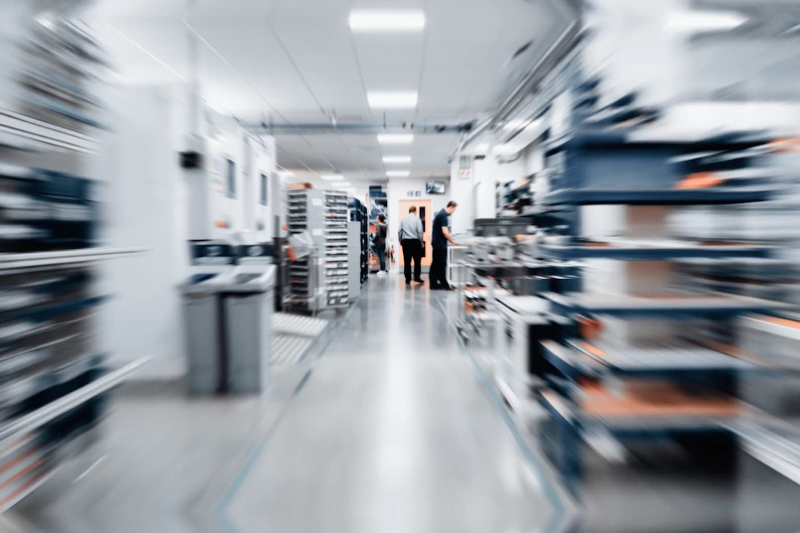 Selection of Gauges, A blurred factory scene featuring several individuals engaged in various activities within the industrial setting.